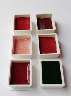 four square containers with different colors of paint in them on a white table top next to each other