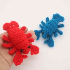 two small crocheted animals are being held by someone's hand on a white surface