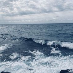 the ocean is very choppy and blue with white clouds in the sky above it