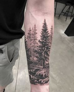 a man's arm with a forest scene on it