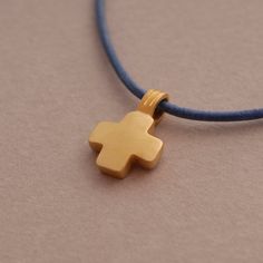 This chunky but tiny cross pendant is a subtle, minimalist necklace that can easily be worn everyday or layered with other necklaces. The dainty cross is handmade of 925 Sterling silver and then coated in gold with a matte finish. In keeping with the purity of the piece, the cross comes on a genuine leather strand in your choice of black or other colors and has been finished nicely with a gold plated sterling silver clasp closure and endings. Leather cord 42 cm L (if you require a longer cord, s Everyday Minimalist Cross Pendant Necklace, Minimalist Daily Wear Cross Pendant Necklace, Minimalist Everyday Cross Necklace, Minimalist Cross Pendant Charm Necklace, Minimalist Yellow Gold Cross Necklace, Adjustable Minimalist Cross Necklace, Minimalist Adjustable Cross Pendant Necklace, Woman In Gold, Tiny Cross