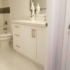 a bathroom with white cabinets and tile flooring