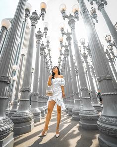 a woman is standing in front of many street lamps and poles with her eyes closed