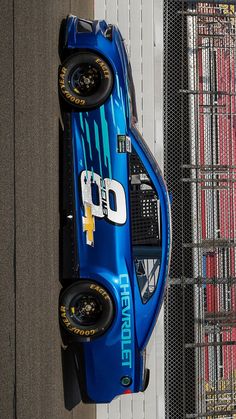 a blue race car parked next to a fence