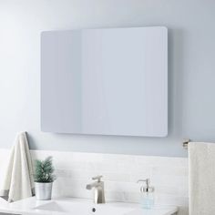 a white bathroom sink sitting under a mirror next to a towel rack and potted plant