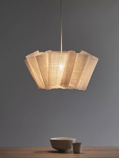 a light that is hanging from a ceiling over a bowl on a table with a bowl underneath it