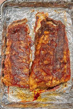 two pieces of meat sitting on top of tin foil