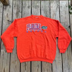 Show your love for the Florida Gators with this vintage Champion University of Florida Gators Orange Crewneck Sweatshirt. This sweatshirt is made from high-quality materials and features the Gators team logo prominently on the front. Perfect for football season and any Gators fan, this sweatshirt comes in size XL and is made by Tultex. perfect for both men and women. It is also perfect for regular season games and is a must-have for any sports fan. This item is made in Mexico and is perfect for Oversized Long Sleeve Throwback Tops, Vintage Letter Print Sweatshirt For Fan Gear, Vintage Crew Neck Tops For Fan Gear, Retro Long Sleeve Sweatshirt For Fans, Retro Fan Gear Sweatshirt For Fall, Vintage Fan Gear Tops With Crew Neck, Vintage Crew Neck Sweatshirt For Fans, Vintage Long Sleeve Fan Gear Tops, 90s Style Tops With Ribbed Cuffs For College