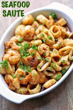 a white bowl filled with pasta and shrimp on top of a wooden table next to a fork