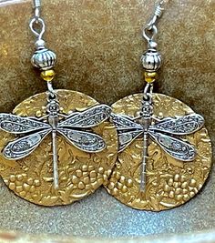 Vintage embossed silver and gold dragonfly dangle earrings. These earrings are so lovely you will want to wear them all the time! They make great gifts although you will want to keep them for yourself! These earrings are enameled brass. They are embossed with a lovely floral design. The silver dragonfly charms are a great contrast to the gold/brass color. These earrings are super lightweight! They are bright and unique and will stand out in a crowd. If you are looking for something unique, then this pair is for you! These earrings are approximately 2 inches long and 1 inch wide. Earwires are sterling silver. All my jewelry comes gift boxed with a custom Shelly Mariposa Design butterfly card ready for gift giving, whether it is a gift for you or someone special. Your satisfaction is very im Dragonfly Jewelry Necklace, Fly Earrings, Unique Dangle Earrings, Dragonfly Gifts, Vintage Dragonfly, Dragonfly Jewelry, Dragonfly Charm, Dragonfly Earrings, Dragon Fly