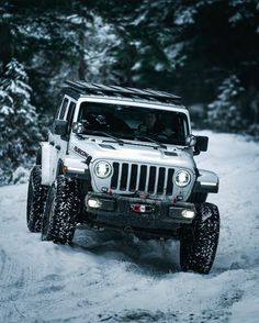 a white jeep driving down a snow covered road