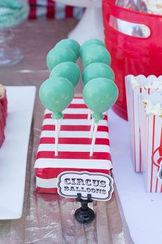 a table topped with red and white striped bags filled with cake pops covered in green frosting