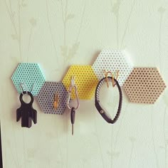 four different colored hexagonal key chains hanging on a wall with two keys attached to them