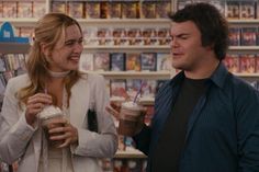 a man and woman standing next to each other holding drinks