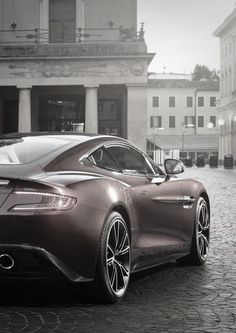 a black and white photo of a car parked in front of a building on a cobblestone street