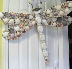 a dragonfly made out of shells is hanging on the door