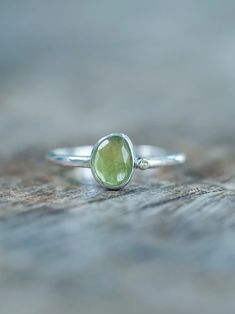 The rose cut peridot (August birthstone) shines alongside a tiny round green sapphire (September birthstone), both held securely in a bezel setting. Pair your peridot ring with peridot earrings to channel a free spirited and joyful vibe. Let this ring be the statement piece that adds a touch of whimsy and elegance to your style. Each piece of our jewelry is handcrafted with love. Fine Jewelry Green Sapphire Ring With Rose Cut Diamonds, Green Sapphire Ring With Rose Cut Diamonds, Green Peridot Birthstone Ring, Dainty Style, Green Peridot Stackable Jewelry, Stackable Green Peridot Jewelry, Peridot Gemstone Stackable Rings For May Birthstone, Stackable Peridot Gemstone Rings For May Birthstone, Green Sapphire Sterling Silver Ring For May Birthstone, Green Sapphire Ring For May Birthstone In Sterling Silver