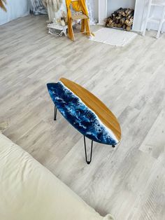 a surfboard shaped table sitting on top of a wooden floor next to a couch