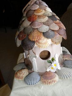 a bird house made out of seashells on a table