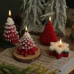 three candles are sitting on top of a piece of music paper and decorated with christmas trees