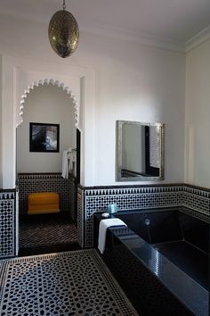 an ornate bathroom with black and white tiles on the floor, walls and bathtub