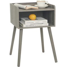 a small wooden table with books and a cup on it, next to an orange