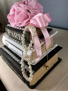 three books stacked on top of each other with pink flowers and pearls attached to them