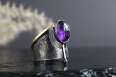 Nice to see you in my store! Stunning brass and pewter ring, featuring a 12 by 10 mm natural amethyst stone. Handcrafted in a unique brutalist style with art deco accents, this ring is a true statement piece. The brass thickness of 0.8mm adds durability and longevity to the design, while the dark patina finish gives it a vintage, rustic look. Perfect for anyone who loves unique and edgy jewelry. Treat yourself or surprise a loved one with a piece that is sure to turn heads and start conversations! Details: - handmade Materials: - natural amethyst (10X12mm) - brass - pewter - dark patina Length of the central part with stone 0.98 inches (2.5 cm) Care instructions: To keep your earrings looking their best, store them in a dry place and avoid exposing them to water or other liquids. You can c Unique Nickel-free Purple Ring, Unique Nickel Free Purple Ring, Unique Purple Nickel-free Ring, Unique Amethyst Open Ring, Art Deco Accents, Pewter Ring, Purple Ring, Dark Jewelry, Edgy Jewelry