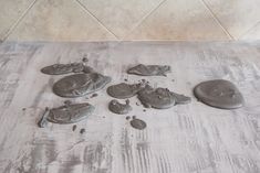 several pieces of metal are laying on the floor in front of a tile wall with white grout