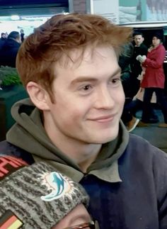 a young man with red hair is smiling at the camera while wearing a hoodie