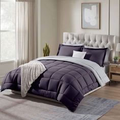 a bed with purple and white comforters in a bedroom