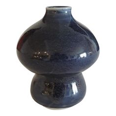 a blue vase sitting on top of a white table next to a black and red object