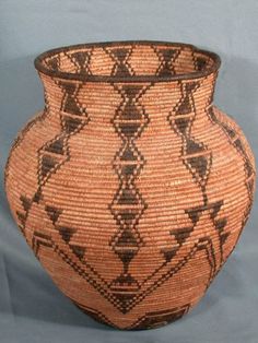 a large brown and black vase sitting on top of a table next to a blue wall