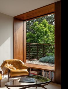 a living room filled with furniture next to a large glass window covered in plants and trees