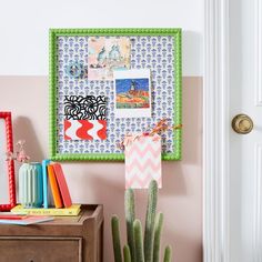 a cactus sits in front of a bulletin board with pictures and magnets on it