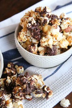 a bowl filled with chocolate covered popcorn on top of a white and blue striped towel