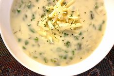 a white bowl filled with broccoli and cheese on top of a table cloth