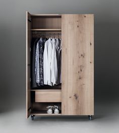 an open wooden cabinet with clothes on it