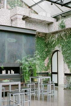 an indoor dining area with tables, chairs and plants growing on the wall behind it