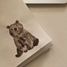 a brown teddy bear sitting on top of a piece of paper