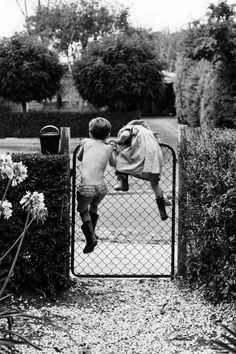 an old black and white photo of two children in front of a fence