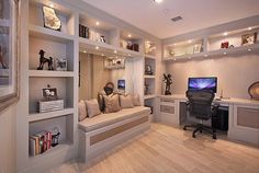 a home office with built - in shelving, desk and computer monitor on the wall