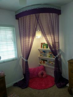 a room with a bed, book shelf and pink rug on the floor in front of it