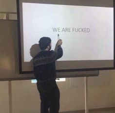 a man standing in front of a big screen giving a presentation to someone who is writing on it