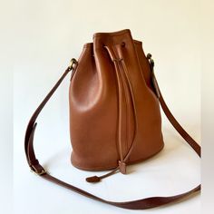 Beautiful Drawstring “Nicolas” Bucket Bag In Hard To Find Color British Tan 10.5” X 12” X 4.5” Drawstring Closure. Main Compartment Has Rear Zip Pocket. Brass Hardware. Strap With 5 Holes For Adjustment, Drop 19”-21” Two Small Spots On Back Of Bag As Shown In Photos. Piping Is In Excellent Condition, Very Clean Interior. Has Original Hangtag. Classic Bucket Bag With Leather Lining, Classic Shoulder Bucket Bag With Dust Bag, Classic Leather-lined Bucket Bag, Classic Cognac Bucket Shoulder Bag, Classic Bucket-shaped Bags For Shopping, Classic Bucket Shape Bags For Shopping, Classic Bucket-shaped Shopping Bag, Timeless Bucket Travel Bag, Classic Shoulder Bag With Bucket Shape