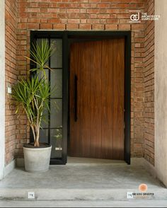 a potted plant sitting in front of a wooden door on the side of a brick building