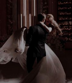 a bride and groom embracing in front of a window