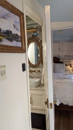 an open door leading to a bedroom with a bed and mirror on the wall above it