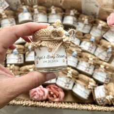 a hand holding a jar filled with baby's breath lotion sitting on top of a table