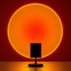 an orange and yellow circle with a black square in the center on a stand against a red background